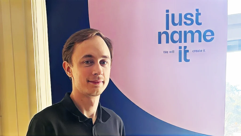 Erik Gårlin i svart pikétröja framför en skylt med Just Name IT:s logotyp.